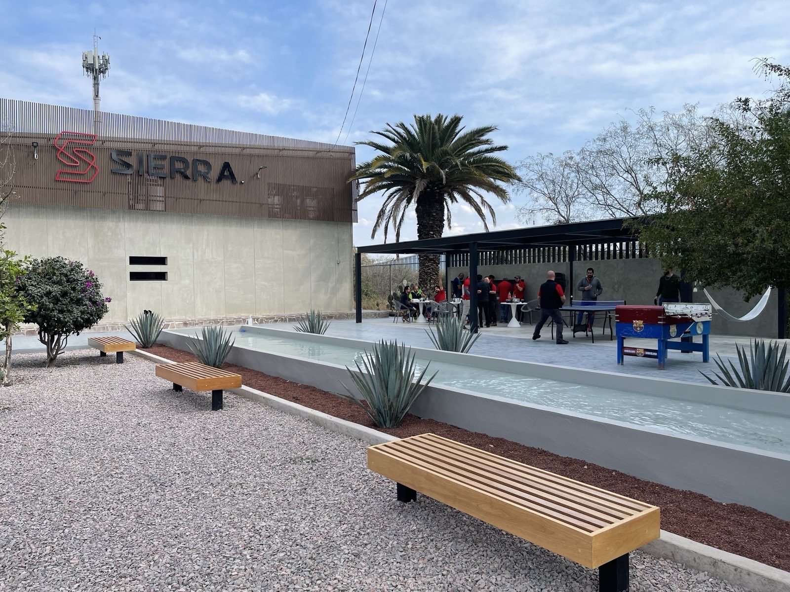 Sierra Manufacturing facade, reflecting pool, and shaded courtyard in use, 2023